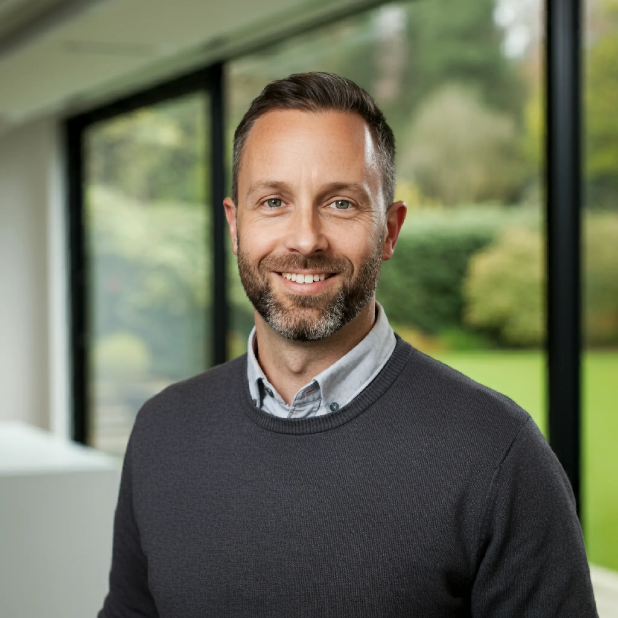 Man in a sweater standing outdoors, smiling