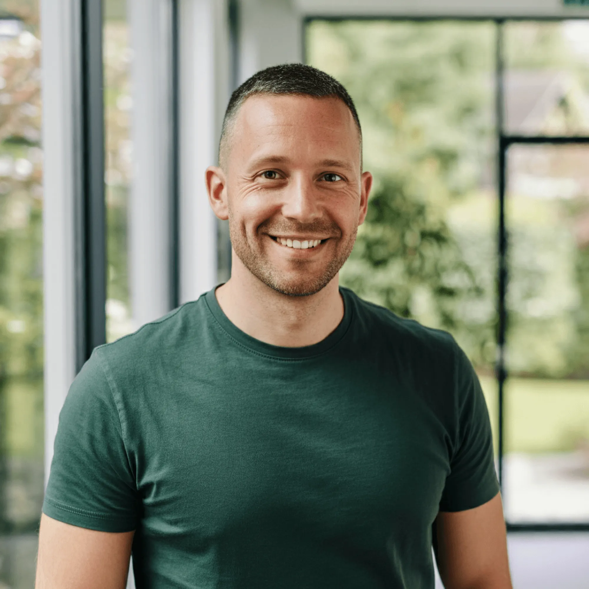 Smiling man in a green shirt standing outdoors